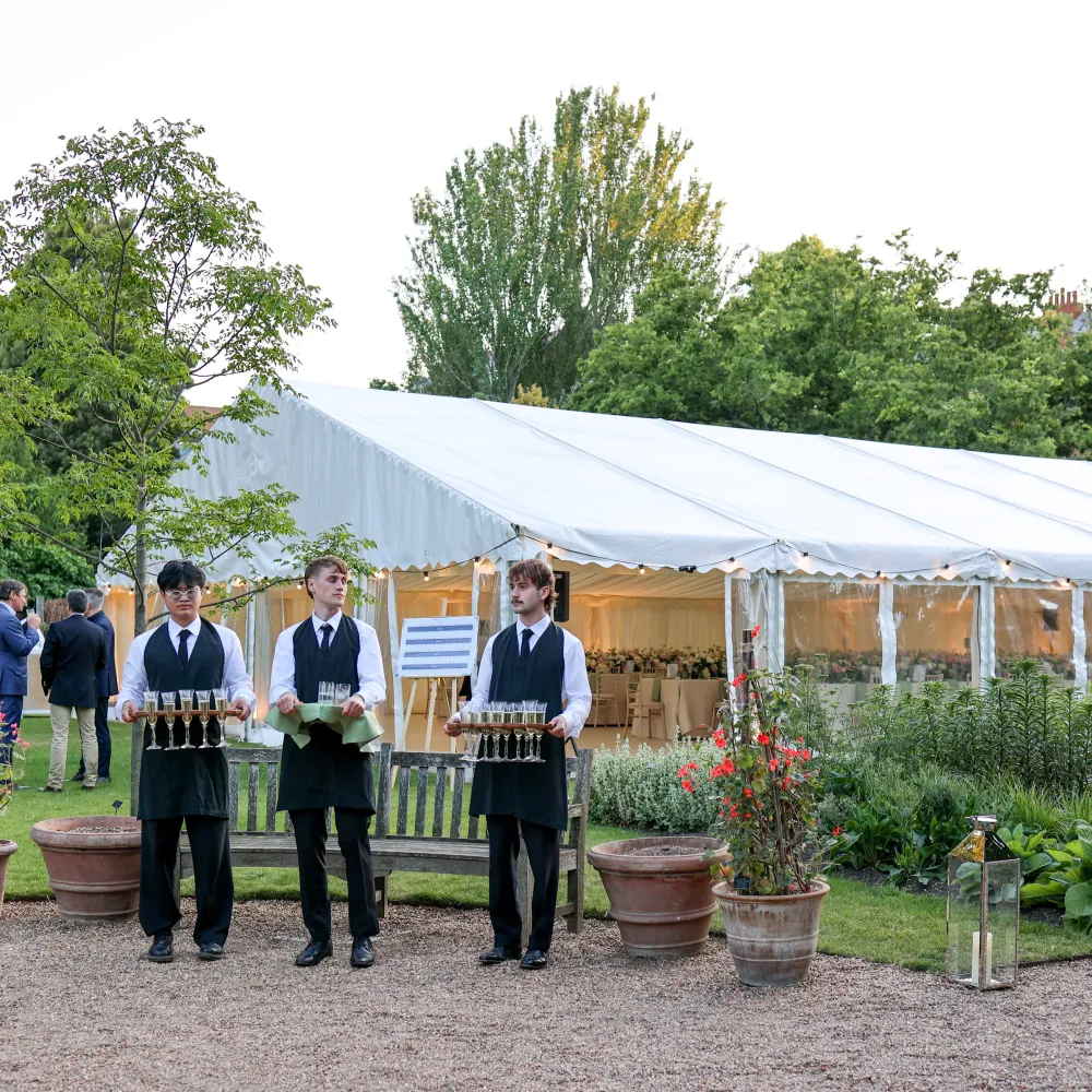 Men holding trays at an event in the garden. Catering team