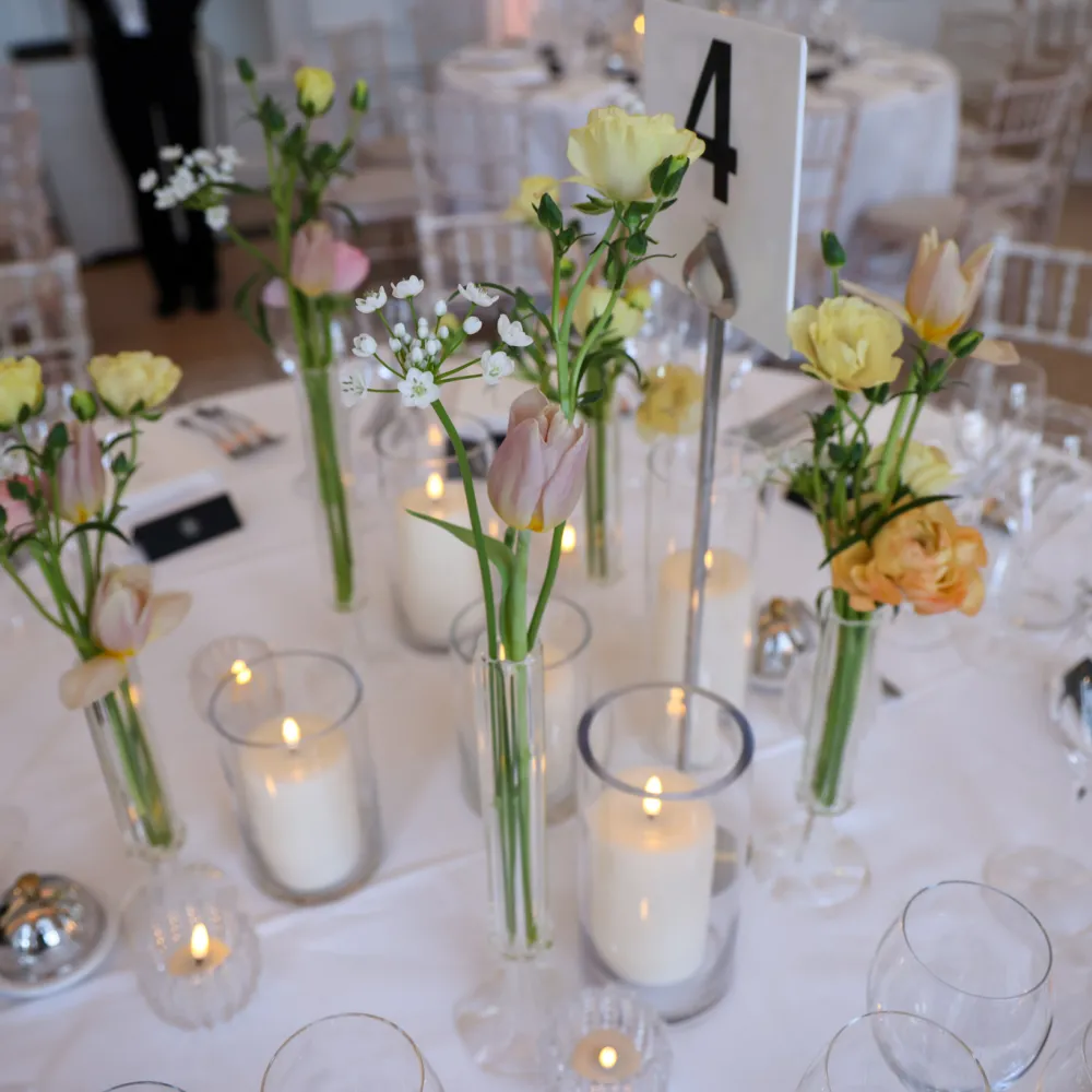close up photo of the floral decors on the round table with candles around