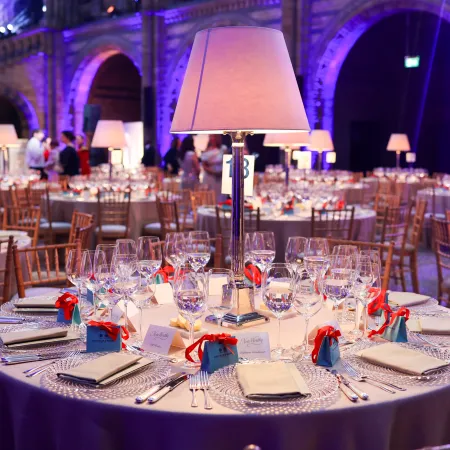dinner setup in Hintze Hall at the Natural History Museum, close up shot of round banquet tables, the iconic suspended blue whale skeleton overhead