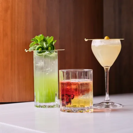 Three cocktails served at the bar at Skywalker Grill, garnished with fresh herbs and fruit.