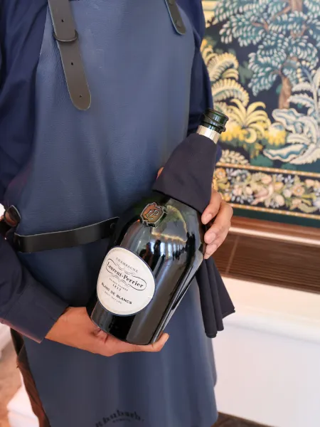 Server wearing a blue apron holding a bottle of Laurent-Perrier Champagn