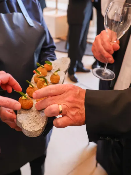 Guests selecting canapés from a server’s tray while holding a Champagne glass