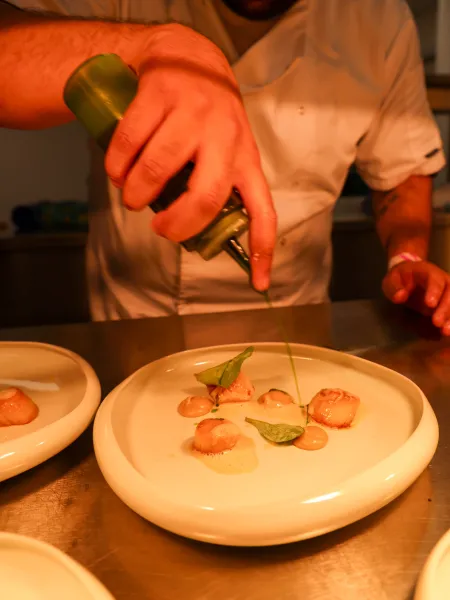 Chef is preparing the starter at the kitchen, pouring the sauce