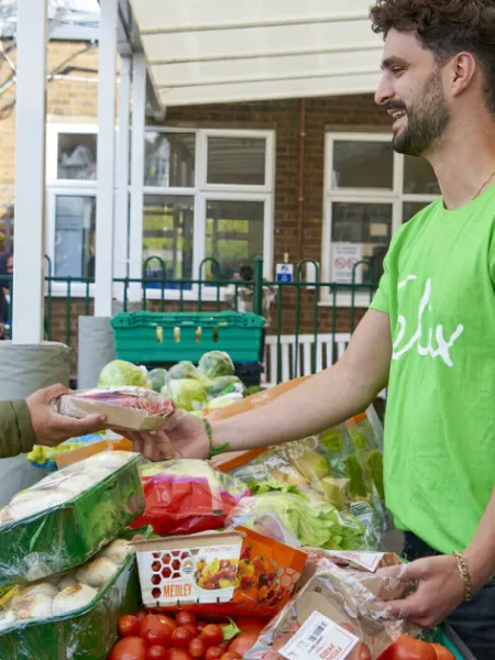 Volunteer from The Felix Project giving food to a woman