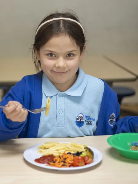 Chefs in schools partnership. Child eating healthy school dinner, smiling.