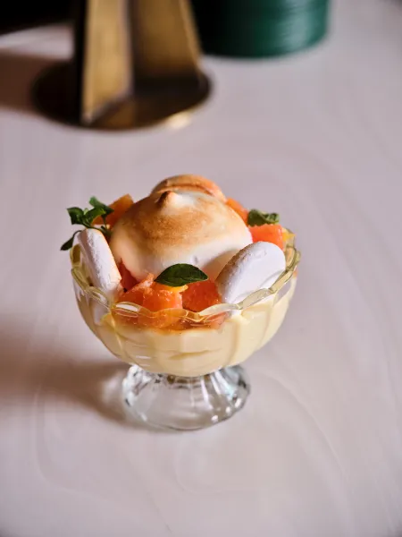 Citrus dessert with toasted meringue, fresh citrus segments and herbs, served in a glass dessert dish at Skywalker Grill.