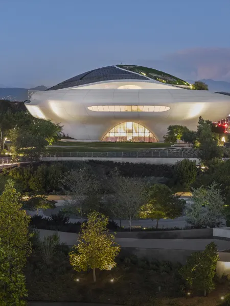 Exterior view of the Lucas Museum of Narrative Art in Los Angeles at dusk, surrounded by landscaped gardens.