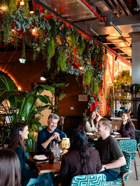 Guests dining together in the vibrant, greenery-filled interior of Elemente Hamburg.