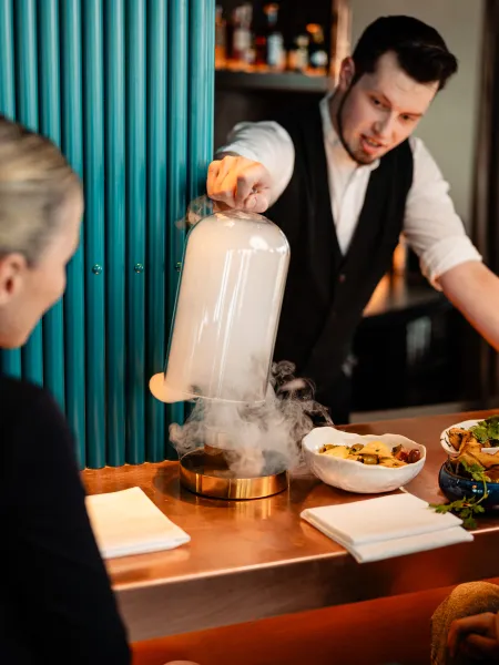 Bartender presenting a smoke-filled cloche tableside at Air Bar 13 Hamburg.