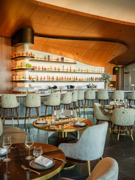Skywalker Grill restaurant interior with curved wooden ceilings, contemporary seating and a central bar with illuminated bottle displays.