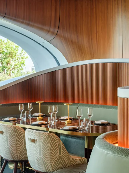 Skywalker Grill restaurant interior with curved wooden ceilings, contemporary seating and a central bar with illuminated bottle displays.