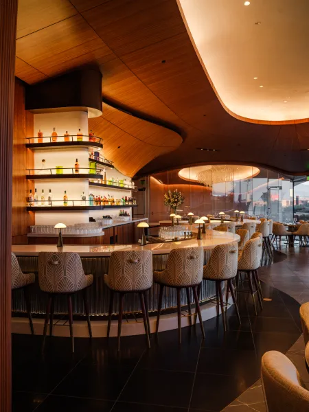 Skywalker Grill bar focus interior with curved wooden ceilings, contemporary seating and a central bar with illuminated bottle displays.