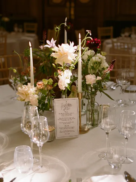A beautifully styled dining table at Chelsea Old Town Hall, featuring seasonal floral arrangements, taper candles, elegant glassware and a printed menu or place card.