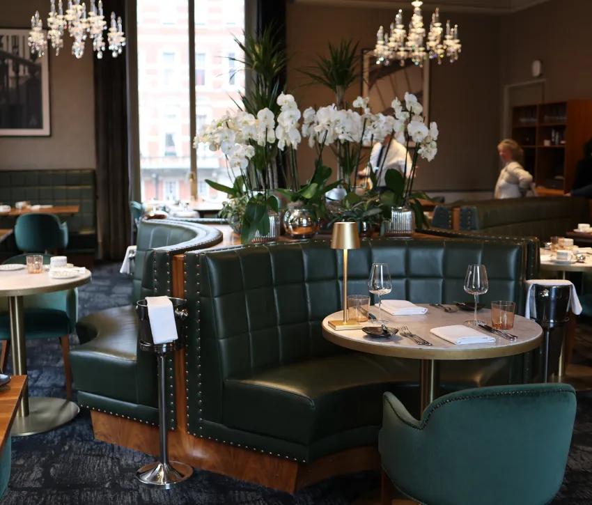 Elegant restaurant interior with green leather seating and floral displays at the Coda, Royal Albert Hall